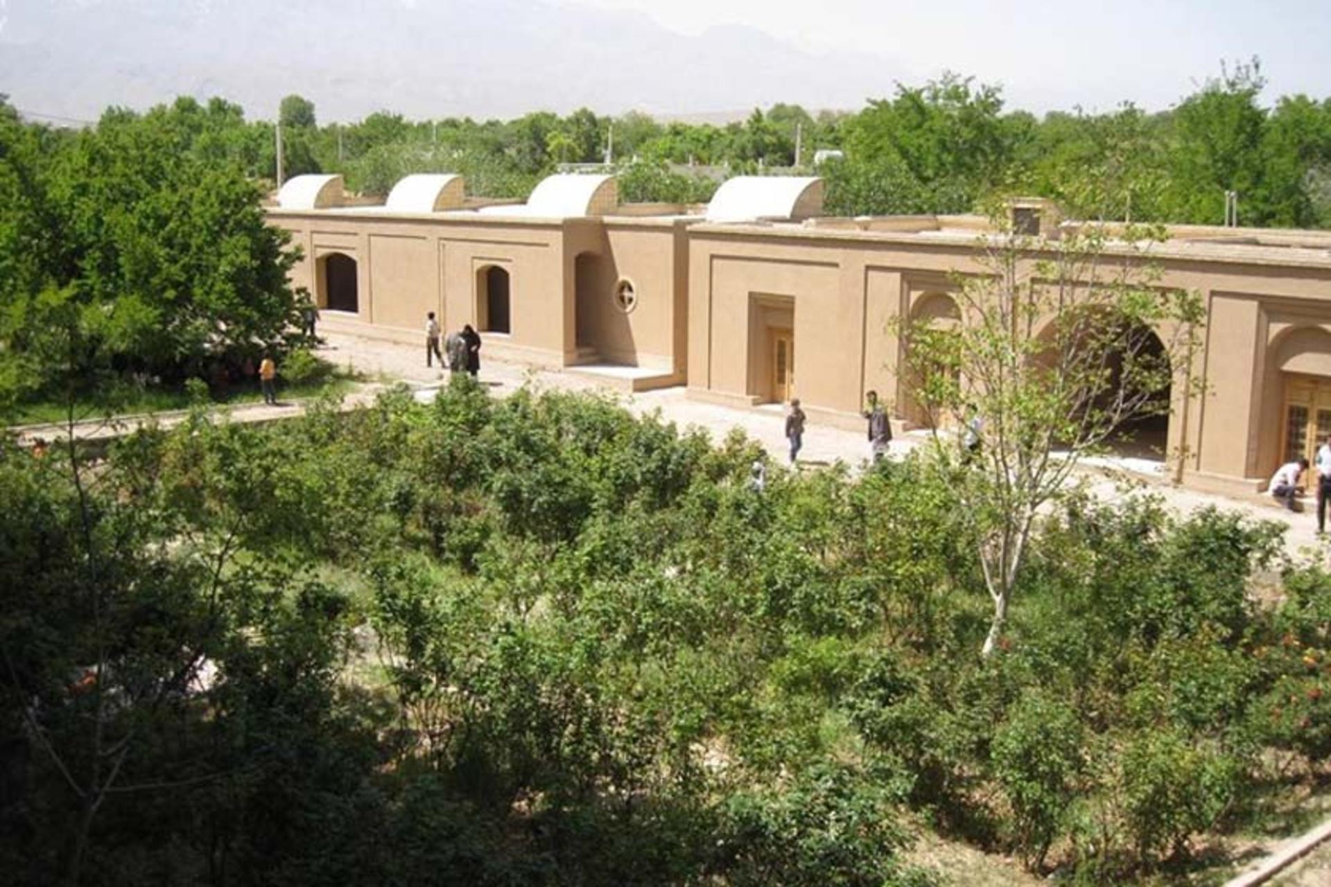 نمایی از عمارت داخلی باغ پهلوانپور مهریز میان درختان بلند و سبز باغ از نمای بالا
