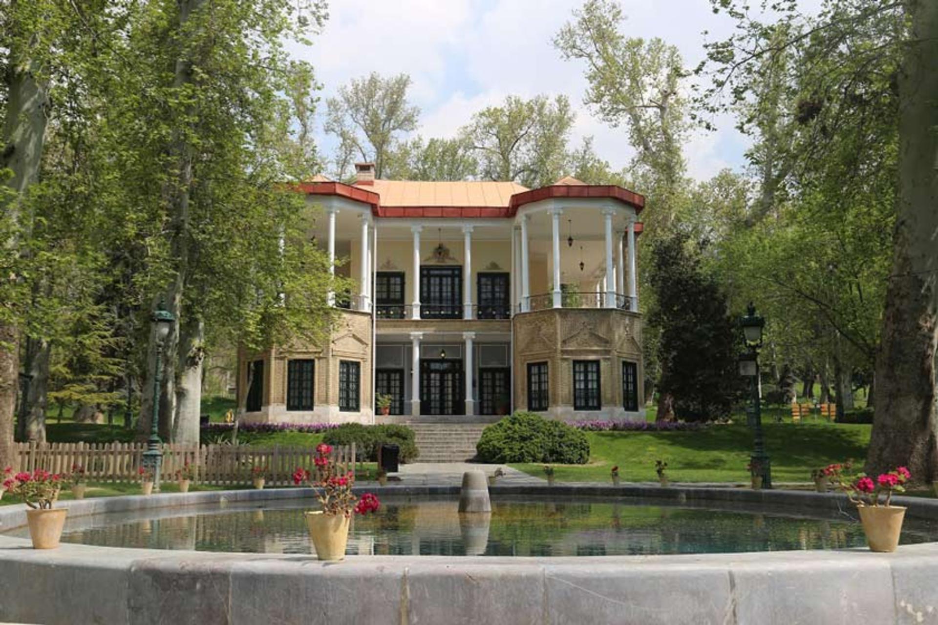 نمایی از کاخ نیاوران میان باغ از نمای پایین پلکان ورودی