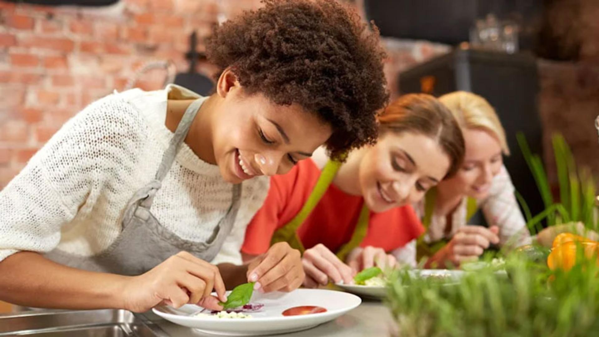 سه زن جوان در حال شرکت در کلاس آشپزی و تزئین غذا