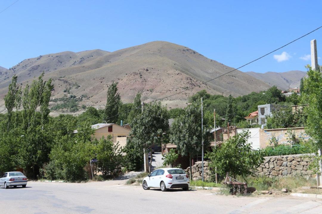 روستای چاشم با خانه‌ها، درختان و کوه در پس‌زمینه