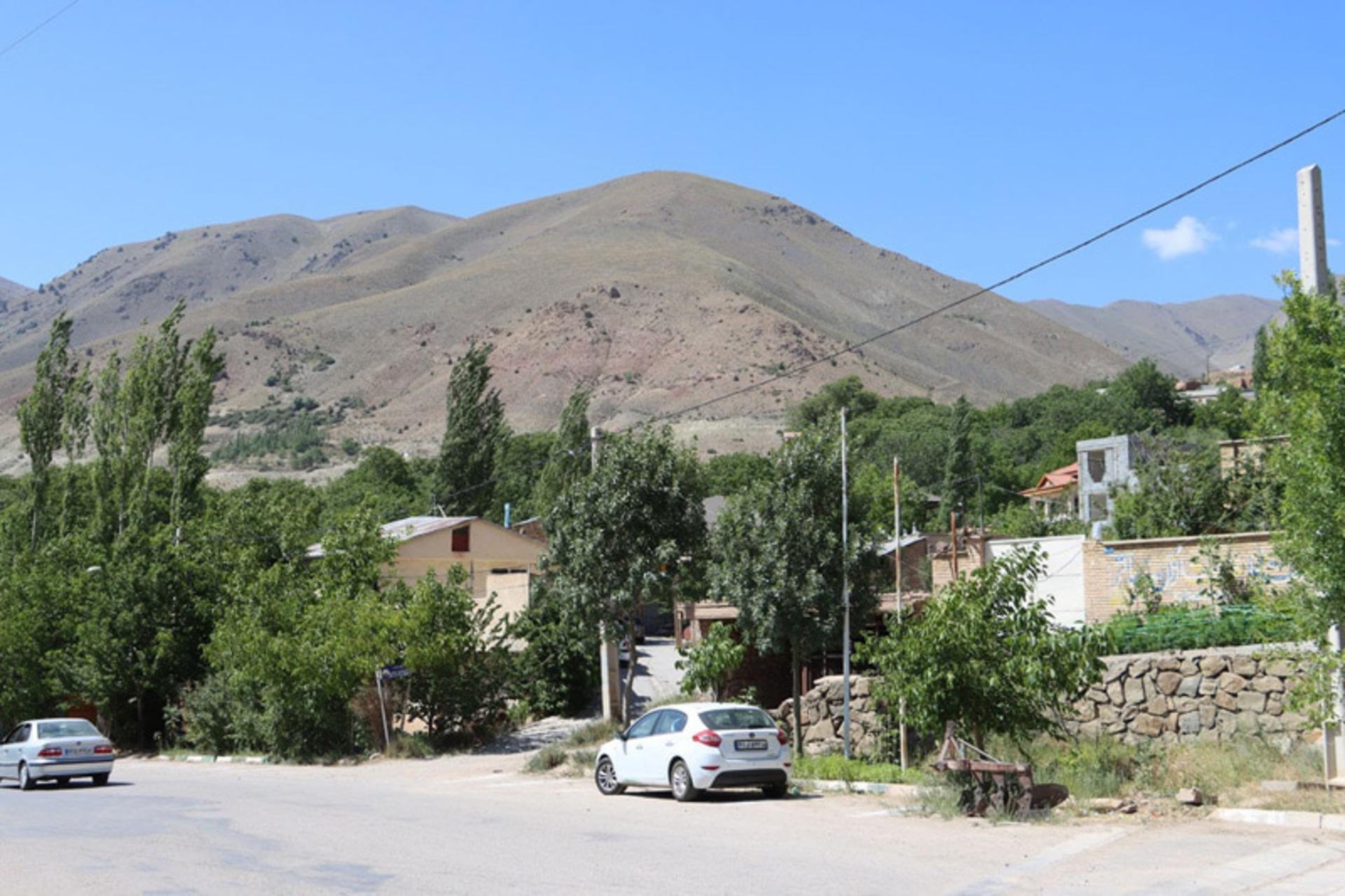 روستای چاشم با خانه‌ها، درختان و کوه در پس‌زمینه