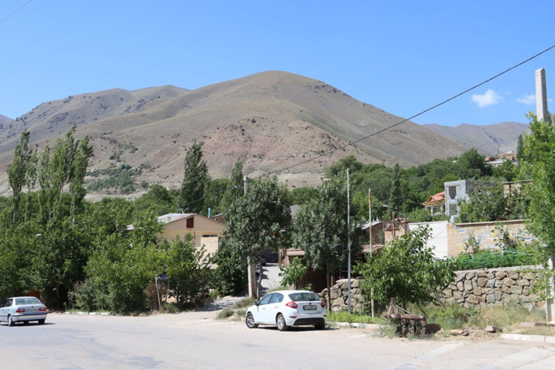 روستای چاشم با خانه‌ها، درختان و کوه در پس‌زمینه