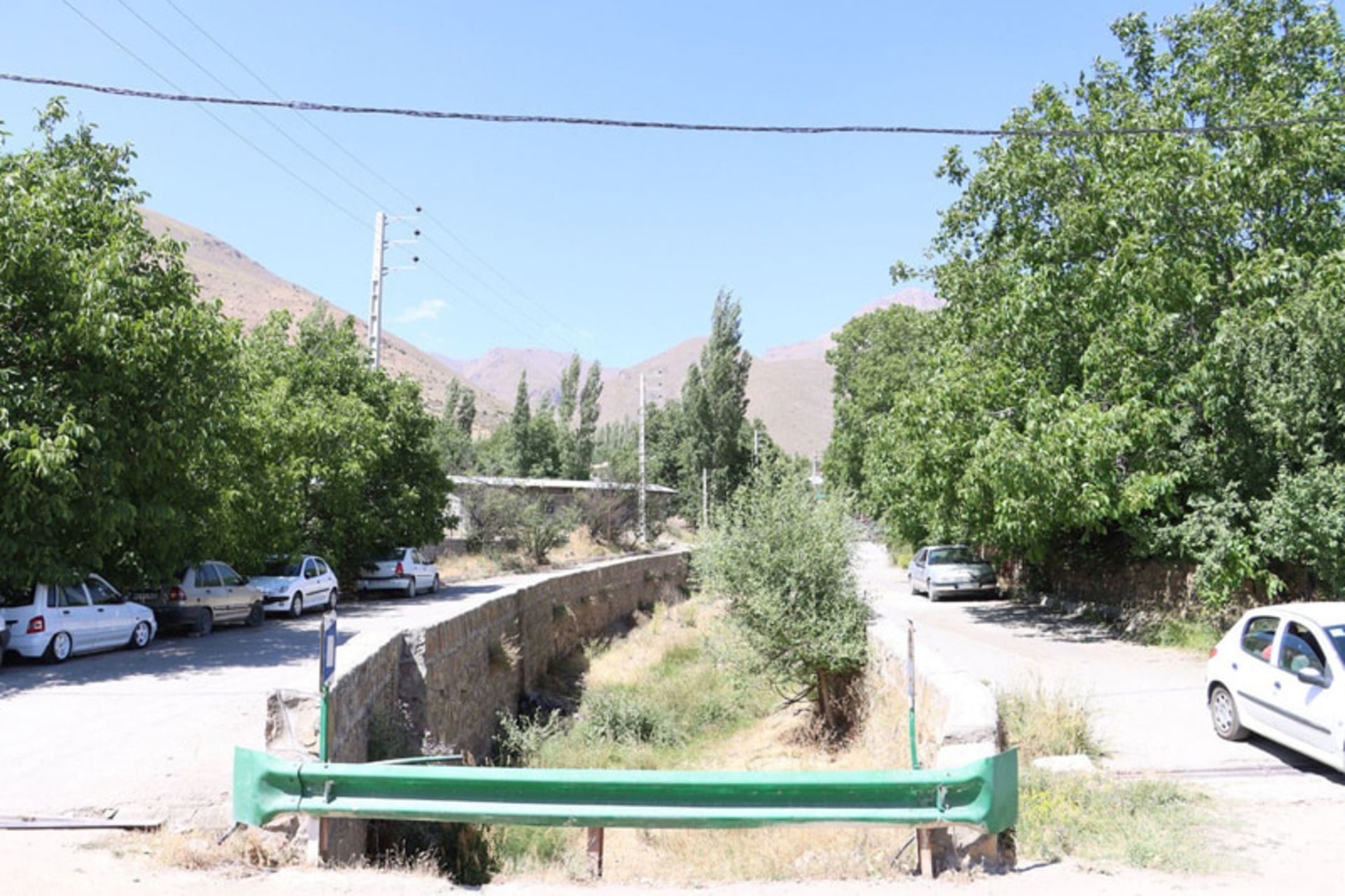 منظره‌ای از روستای چاشم با جاده، درختان و جوی آب