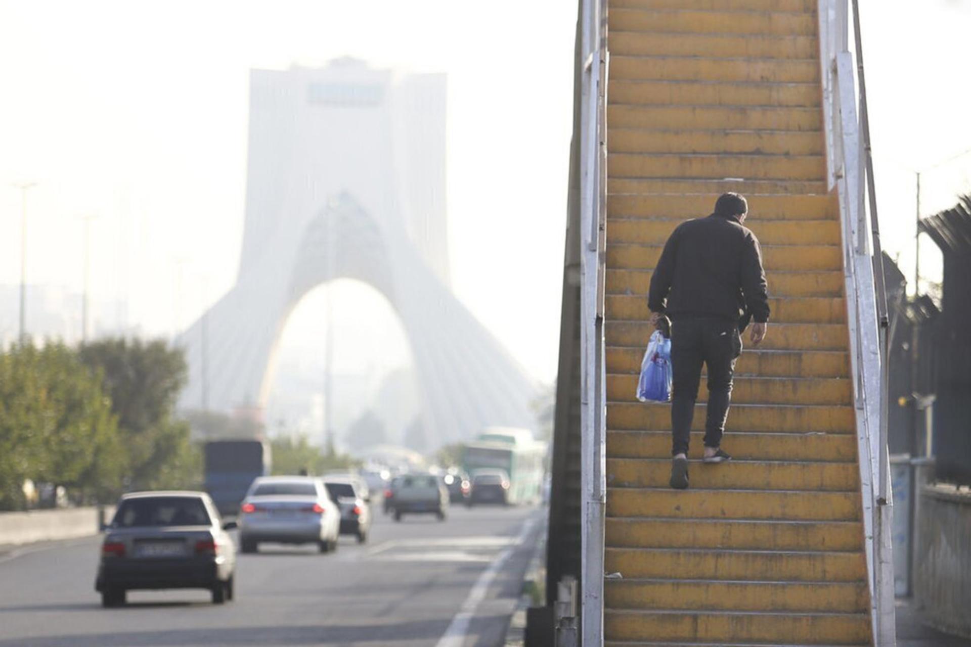 مردی از پله‌های پل عابرپیاده بالا می‌رود