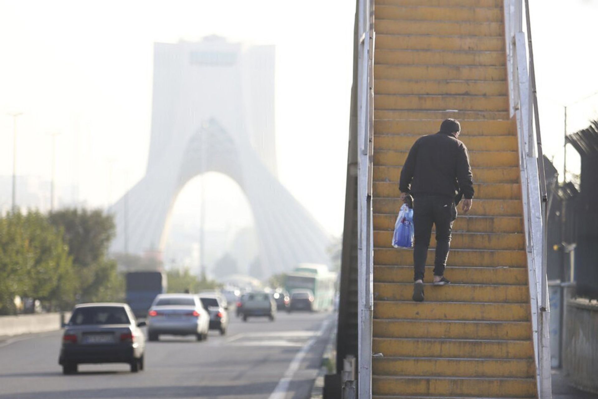 مردی از پله‌های پل عابرپیاده بالا می‌رود