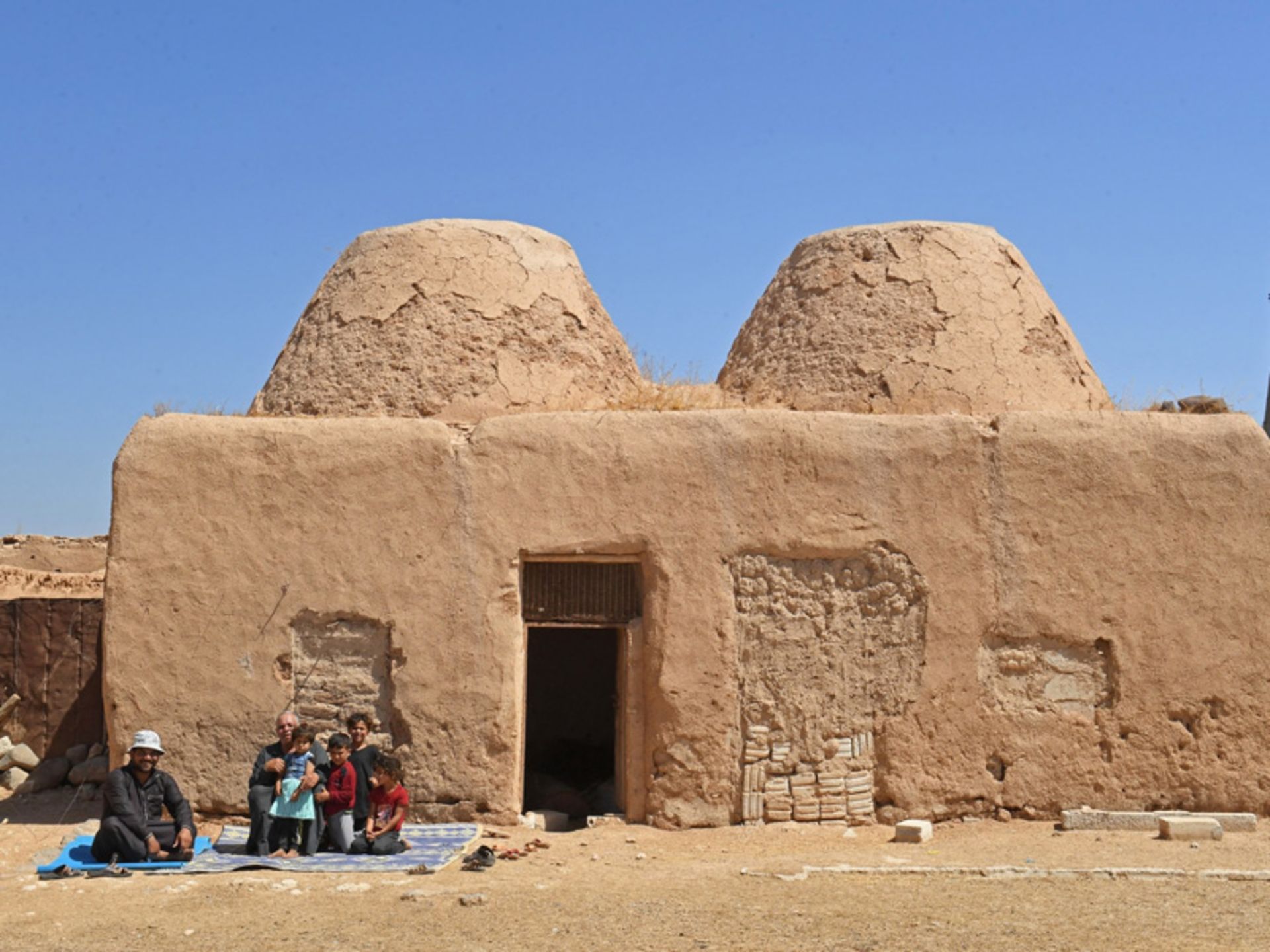 مردم کنار خانه های گلی در شهر بیابانی