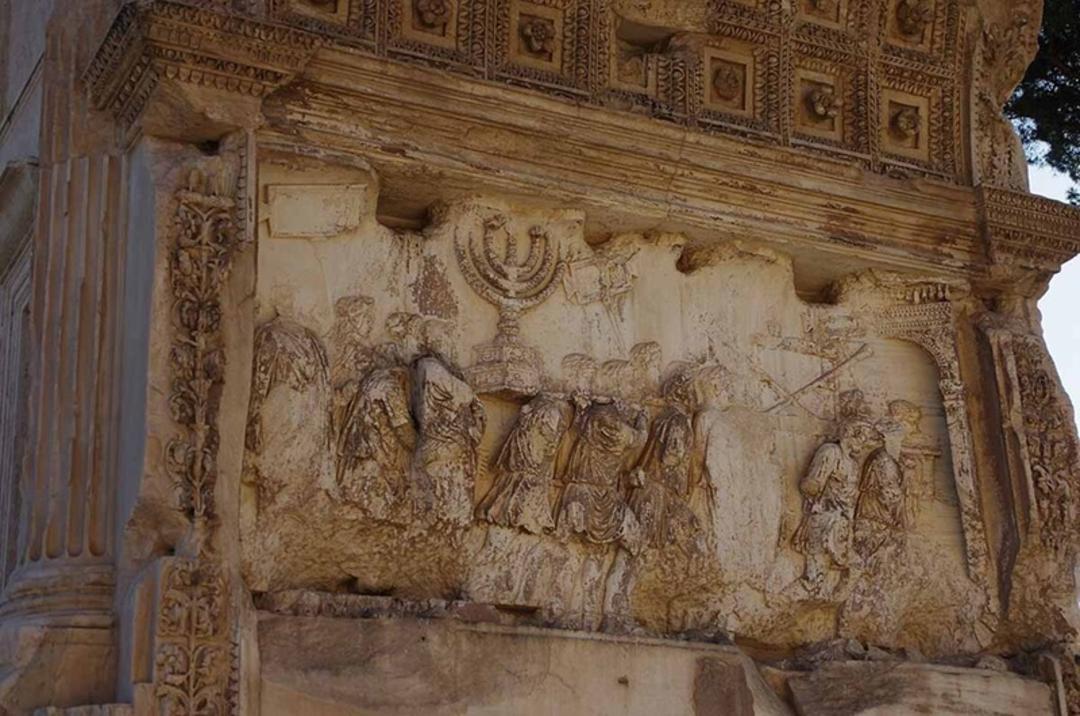 نقش‌برجستهٔ طاق تیتوس که منورا (شمعدان هفت‌شاخه) را در حال حمل در رژهٔ روم نشان می‌دهد، عکسی از پائولو ویلا، ۲۰۲۲ میلادی.