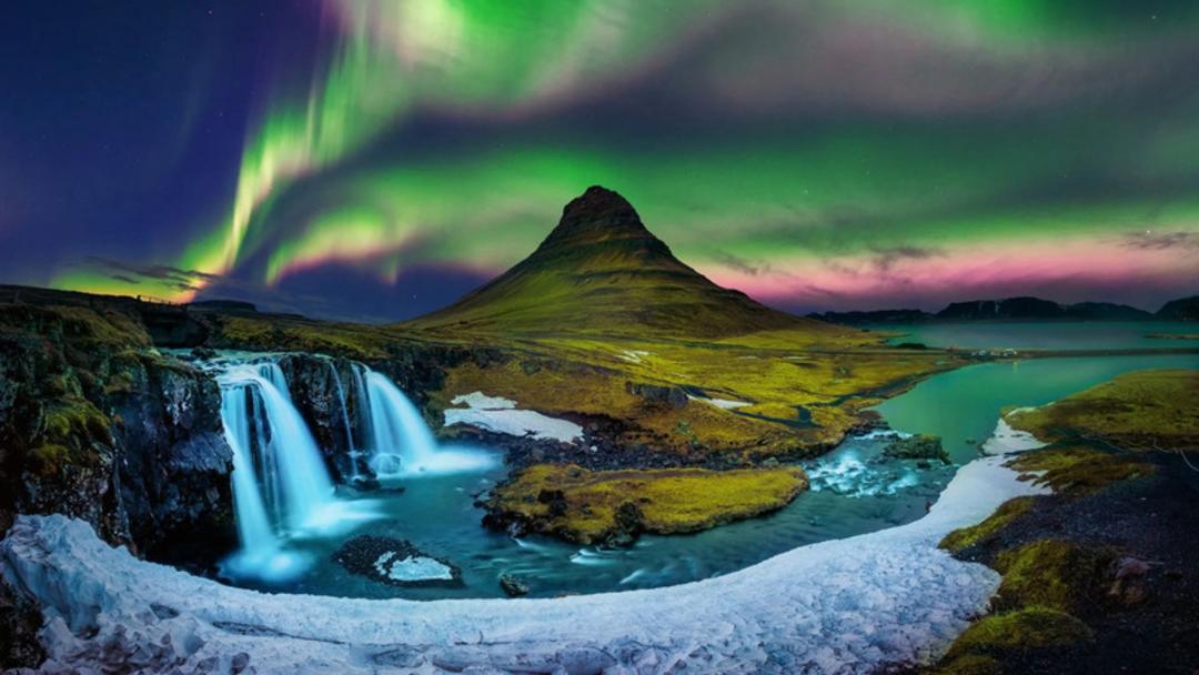 شفق قطبی (Aurora Borealis) در آسمان بالای کوه کیرکیوفل (Kirkjufell) و آبشار