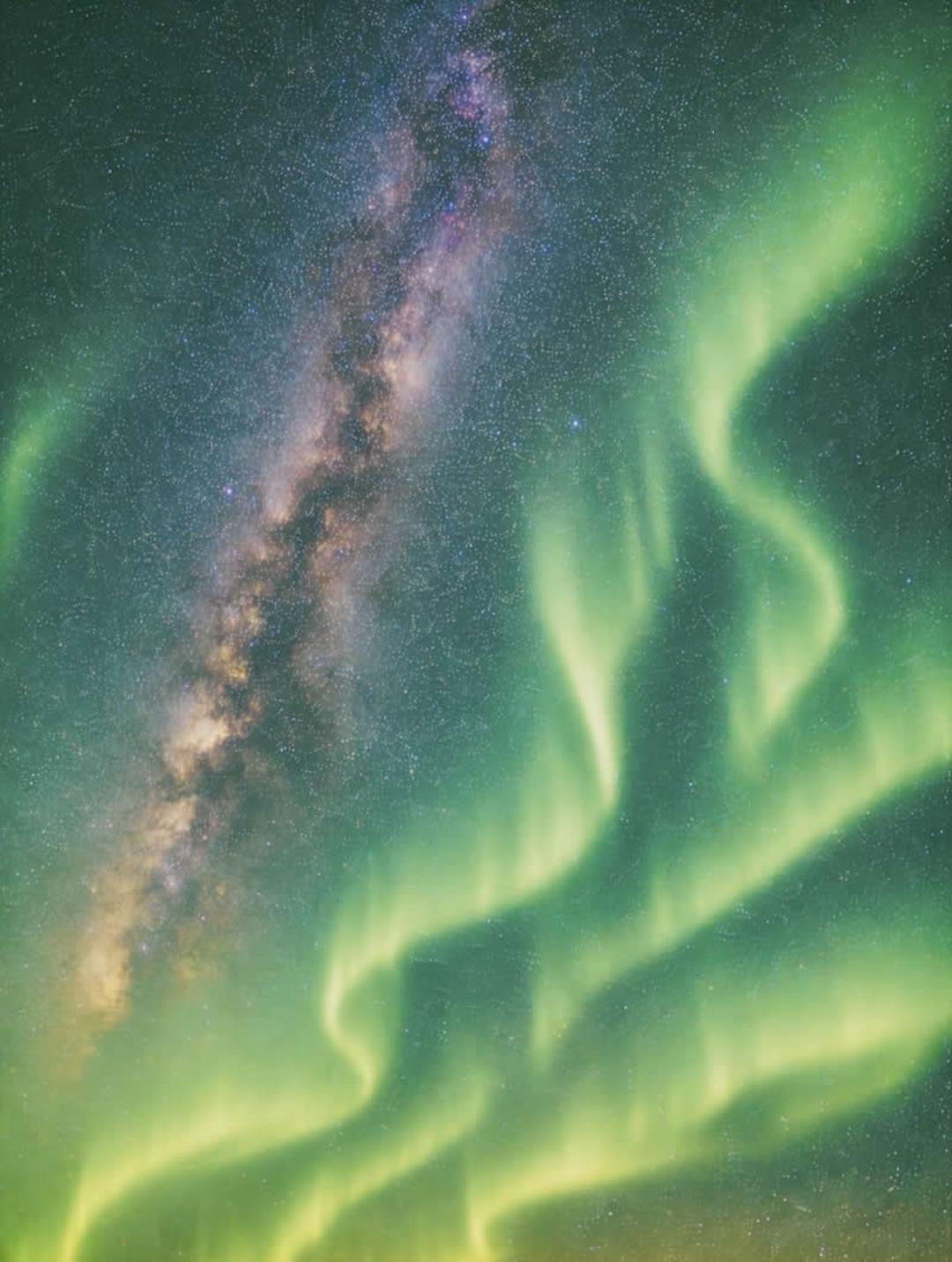 شفق قطبی (Aurora Borealis) سبز رنگ در کنار کهکشان راه شیری در آسمان شب
