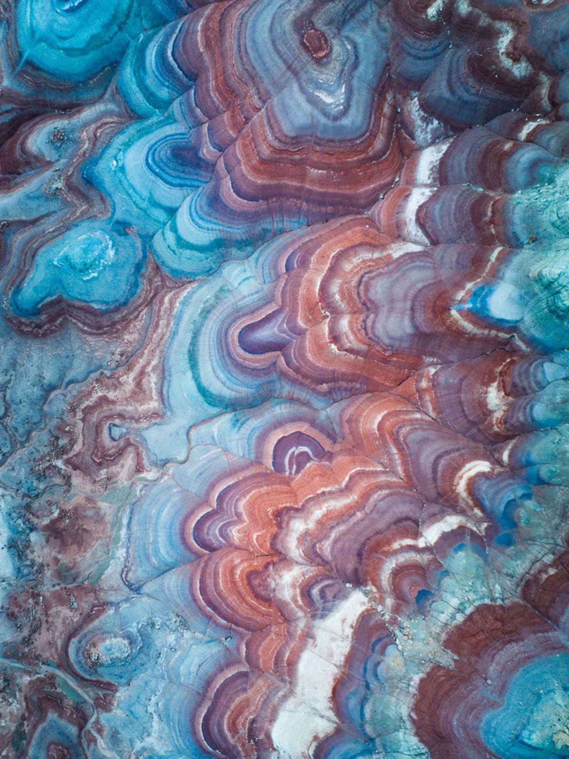 عکس هوایی از بافت صخره‌ای لایه‌لایه با الگوهای مدور و رنگی