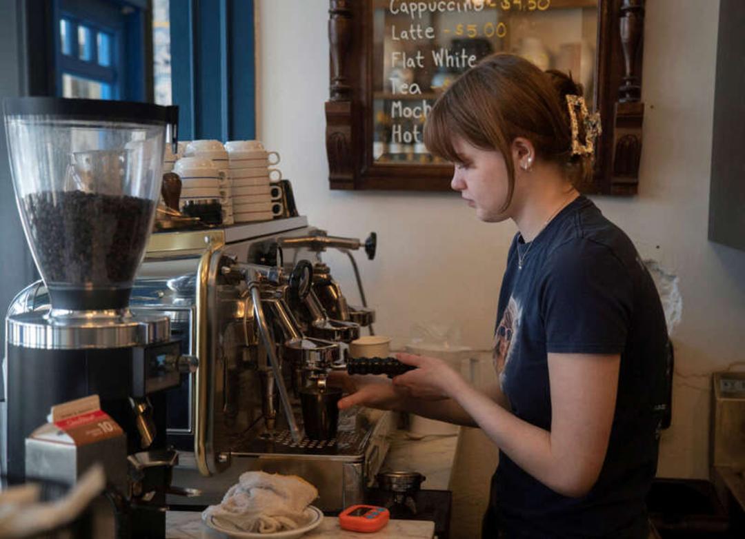 باریستا (Barista) در حال کار با دستگاه اسپرسوساز در محیط کافه