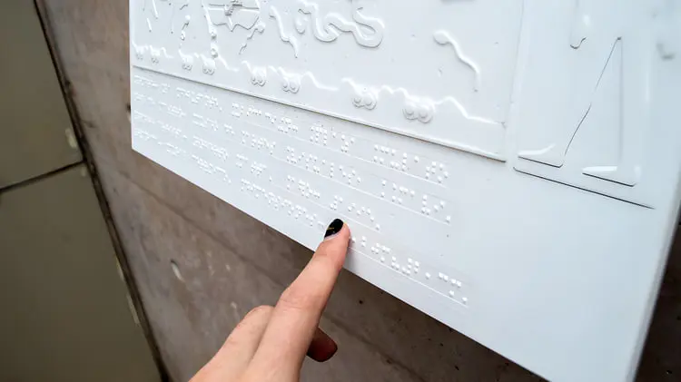 پنل سفید دارای نوشته‌های برجسته بریل (Braille) برای افراد نابینا