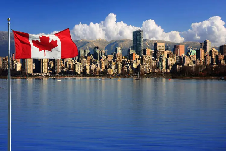 پرچم کانادا (Canada) در مقابل آسمان‌خط شهری با کوه‌های پوشیده از برف