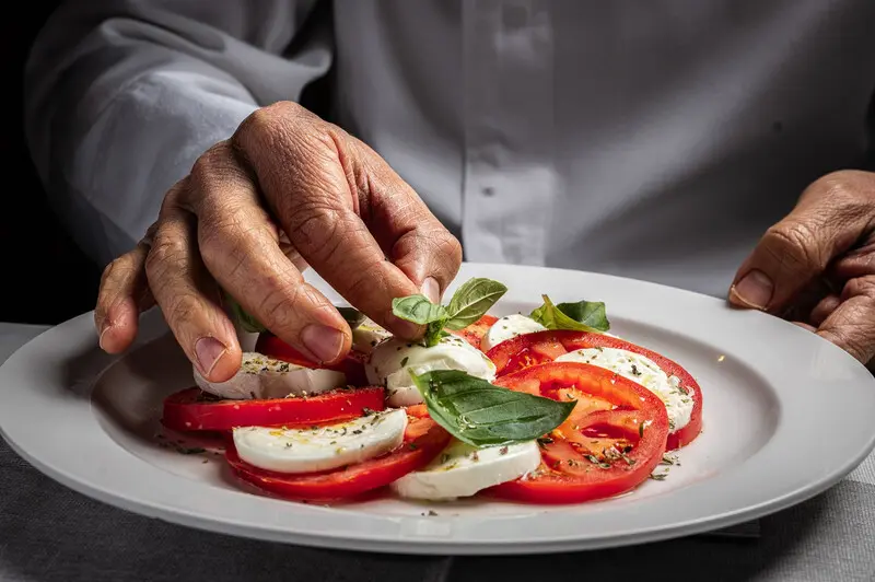 سالاد کاپره (Caprese Salad) با تکه‌های گوجه‌فرنگی، پنیر موتزارلا و برگ ریحان