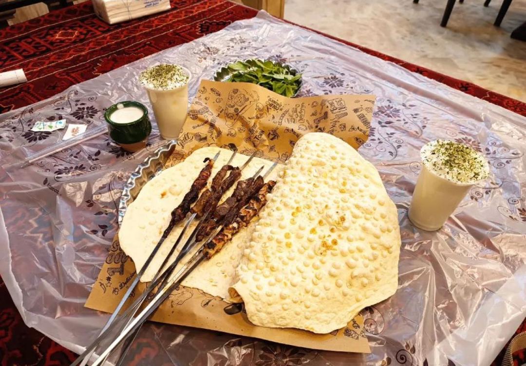 جوجه کباب روی نان سنگک در کنار نوشیدنی‌های سنتی