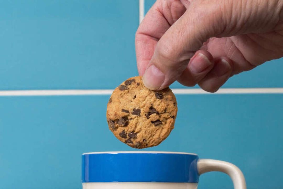 بیسکویت شکلاتی (Chocolate Chip Cookie) در حال غوطه‌ور شدن در فنجان چای