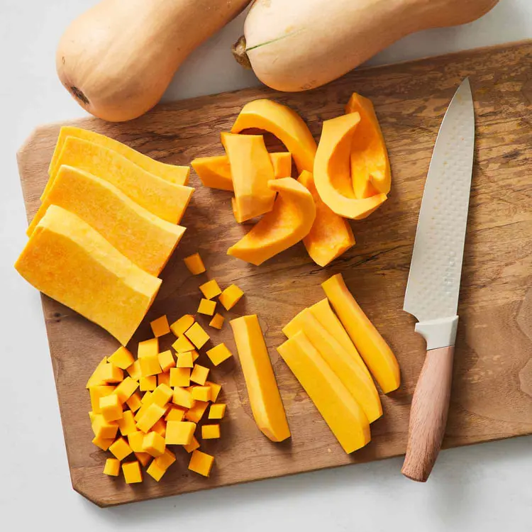 کدو حلوایی (Butternut Squash) خرد شده به صورت قطعات مختلف روی تخته چوبی
