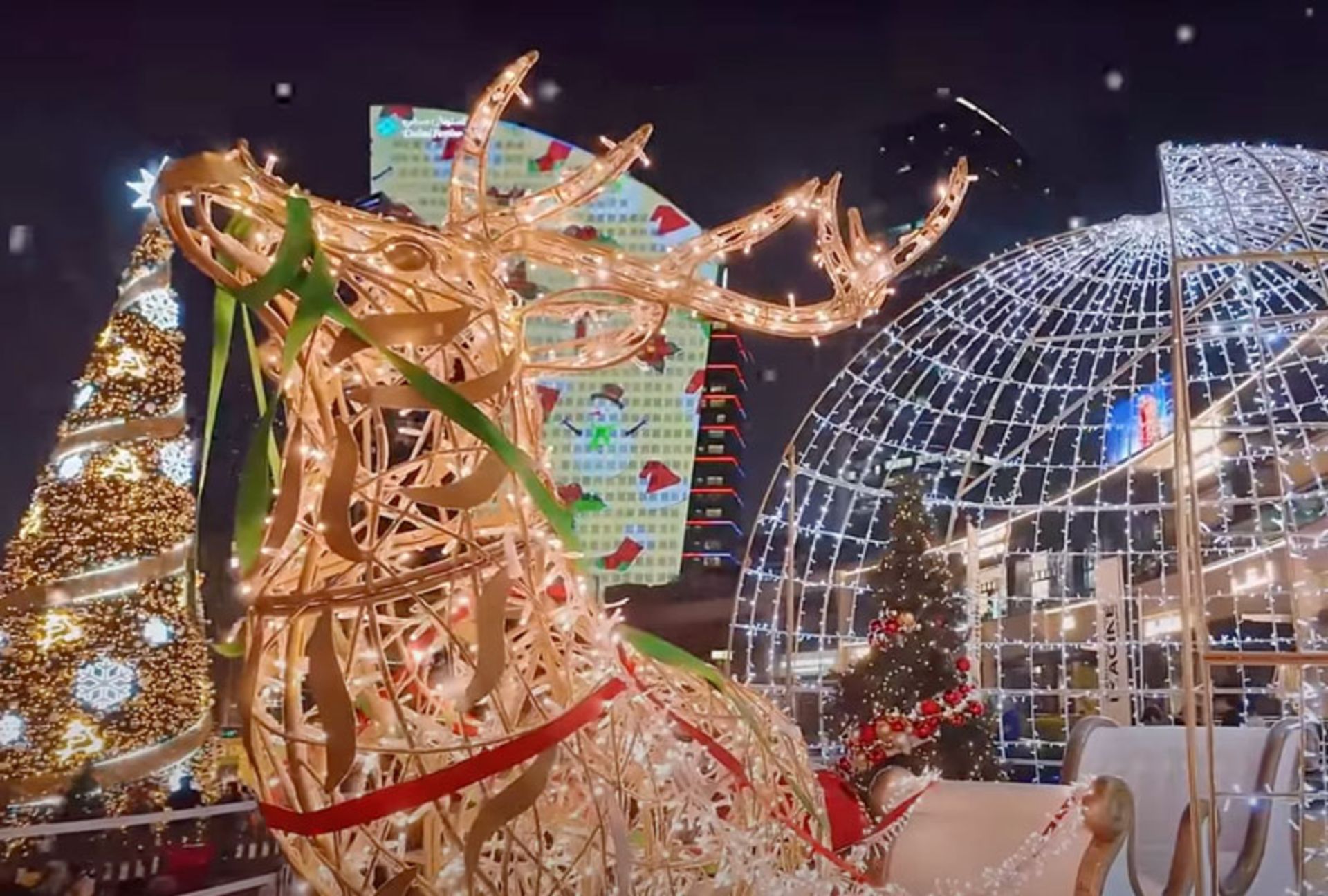 تصویری از یک بازار کریسمس شبانه با یک مجسمه گوزن شمالی در دبی