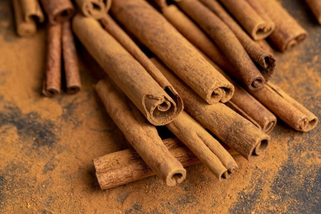 چوب‌های دارچین روی سطح پوشیده شده با پودر دارچین
