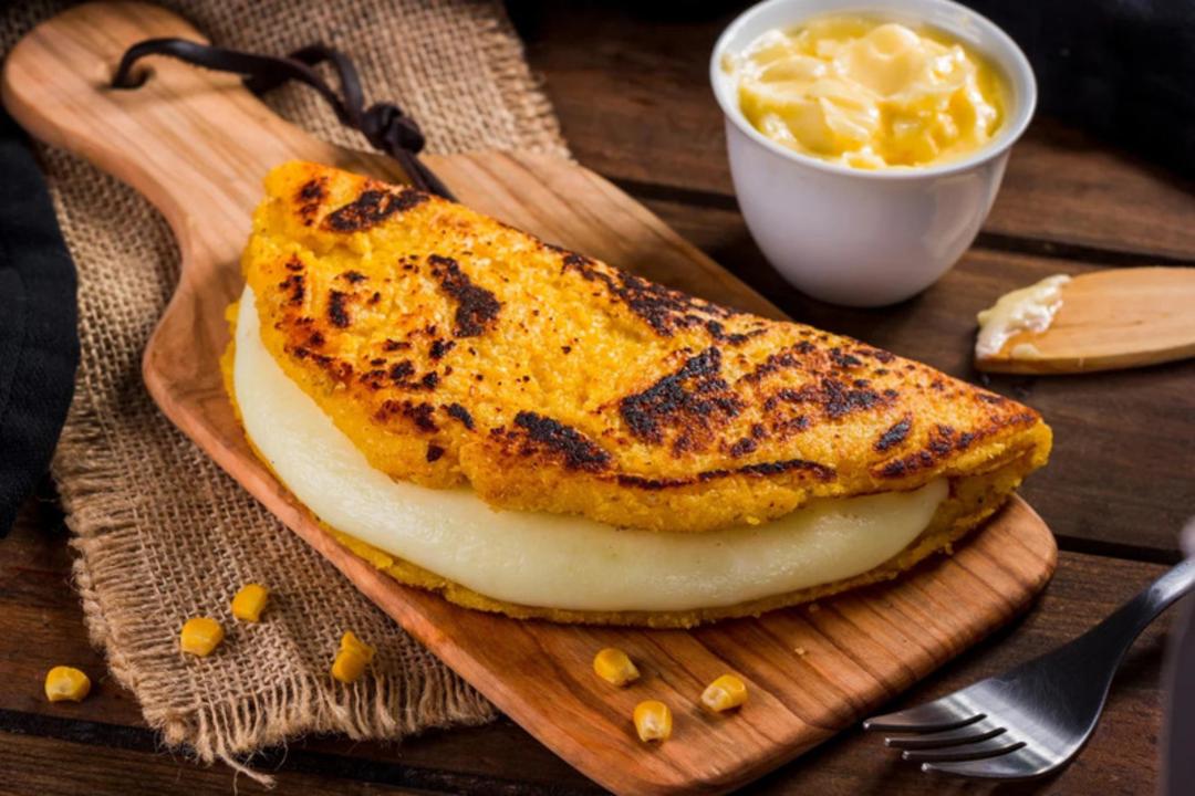 پنکیک ذرت (Corn Pancake) با لایه ضخیم پنیر ذوب شده روی تخته چوبی