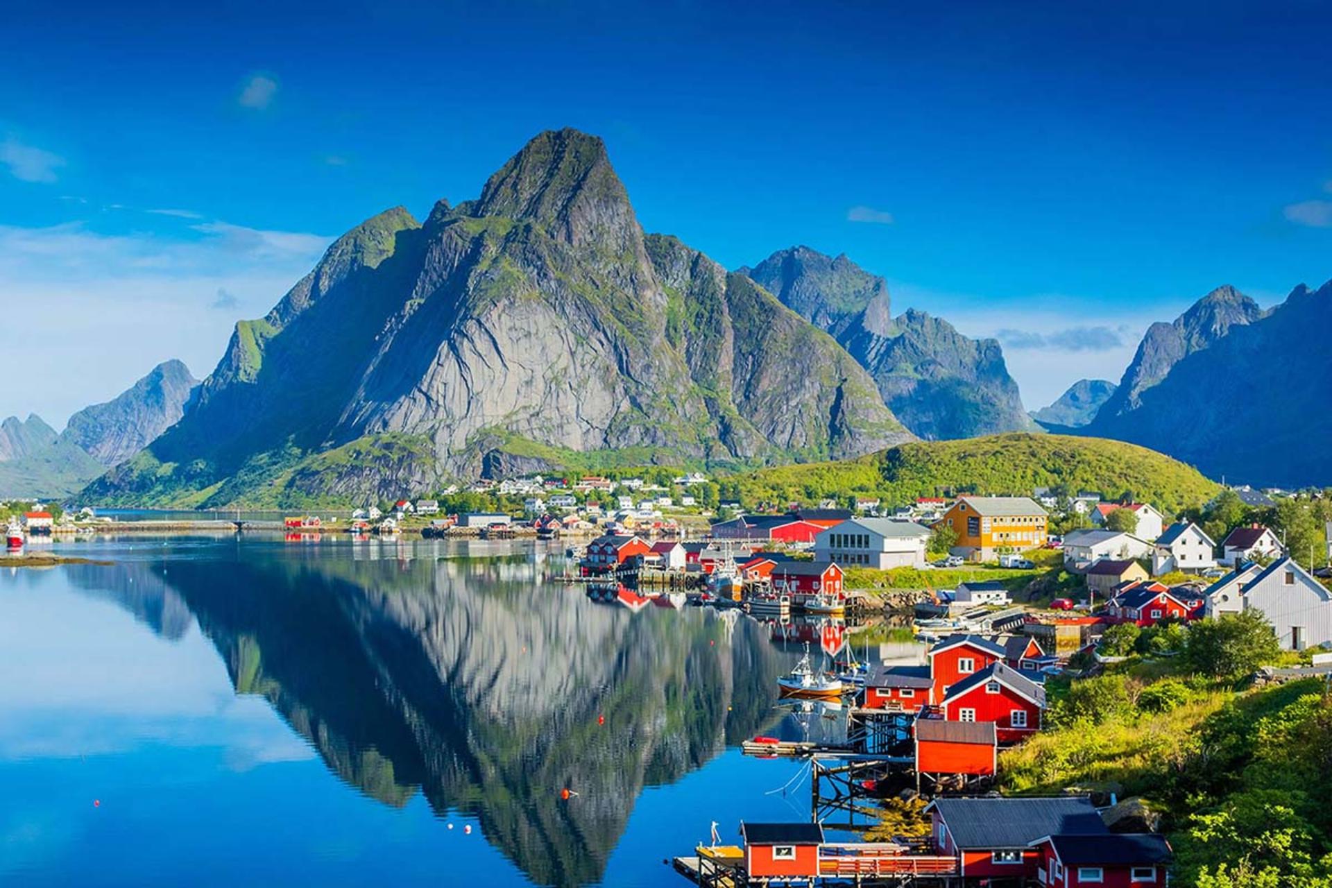 روستایی ساحلی با خانه‌های قرمز سنتی در کنار آب و کوه‌های مرتفع 