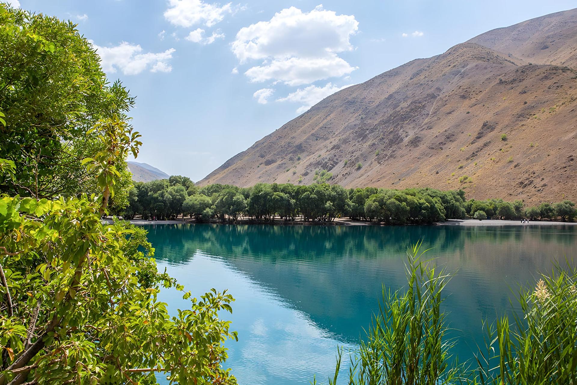 آب‌های زلال دریاچه گهر (Gahre Lake) در میان کوه‌های خشک و درختان سبز