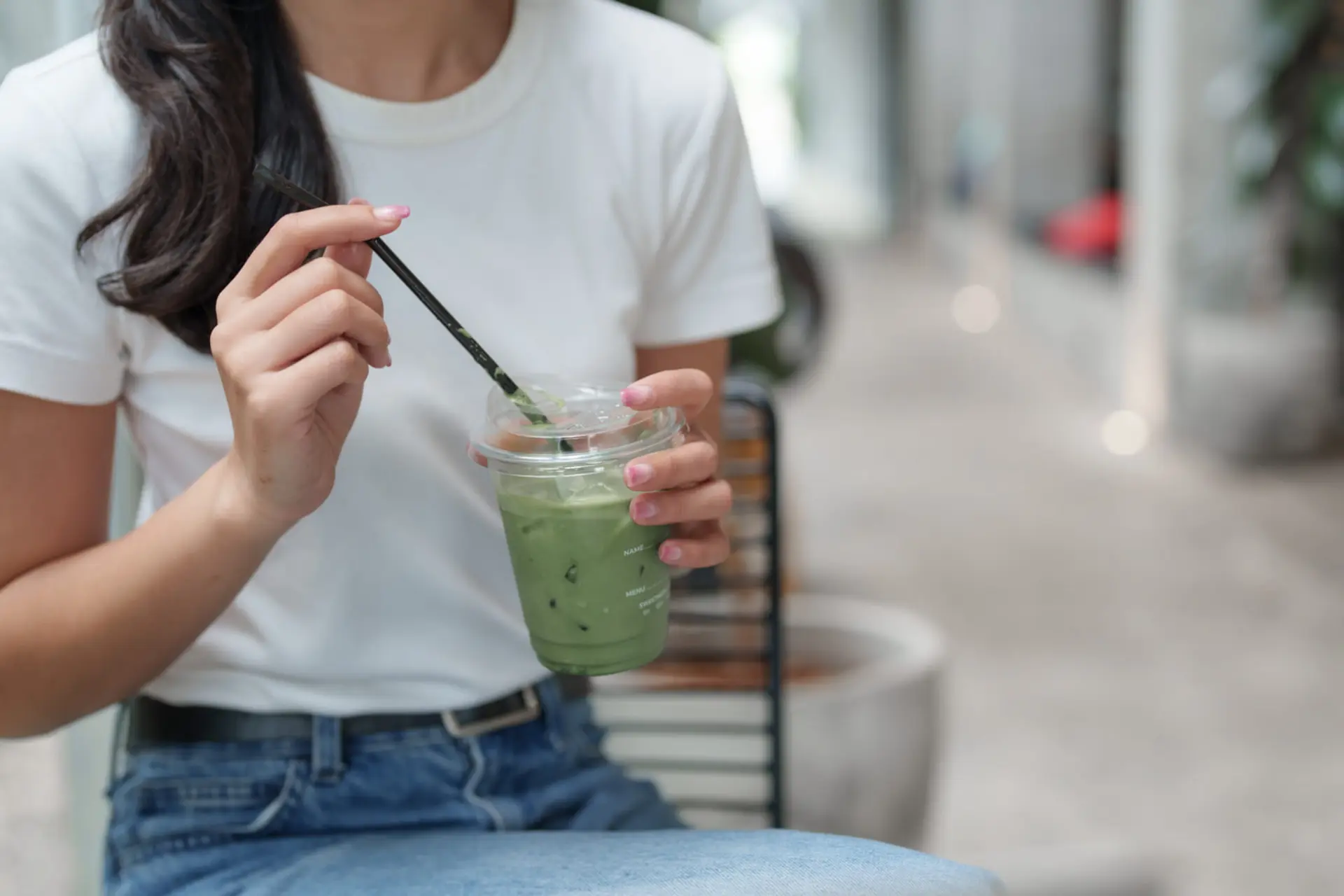 نوشیدنی ماچا (Matcha) در لیوان پلاستیکی در دست یک زن