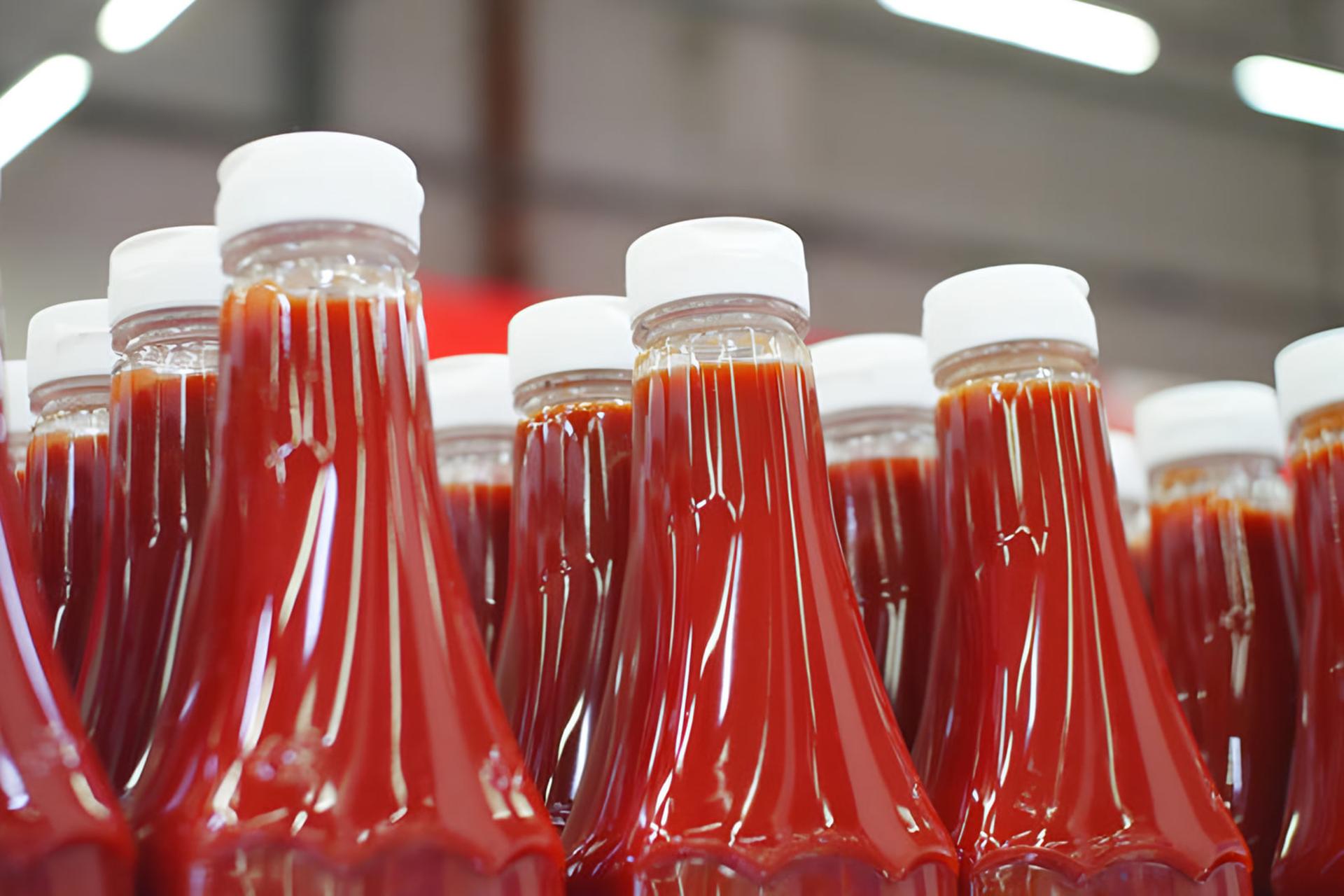 بطری‌های سس گوجه‌فرنگی (Ketchup) با درپوش سفید در قفسه فروشگاه