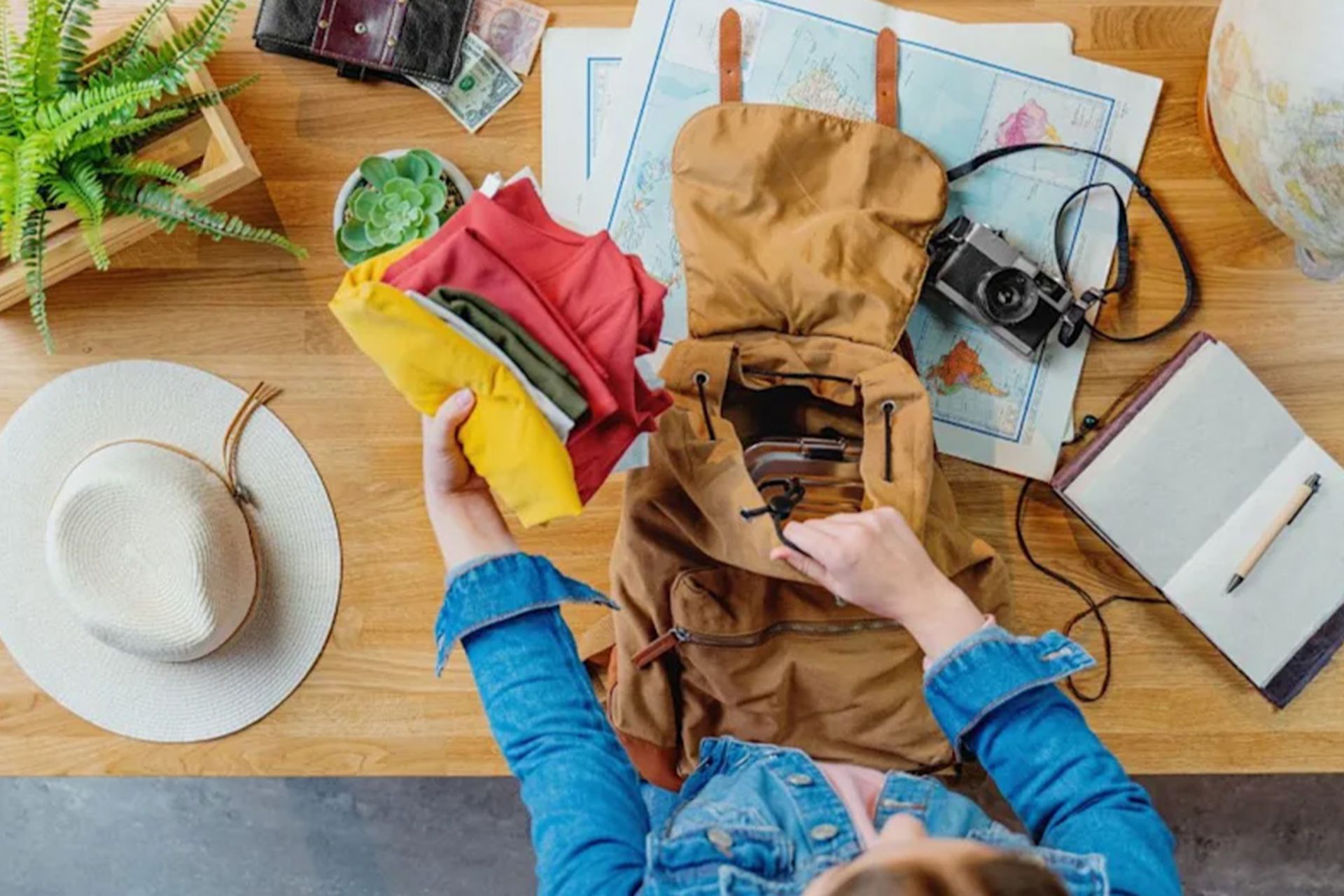 نمای از بالا از فردی که لباس‌های سبک را در کوله‌پشتی می‌گذارد