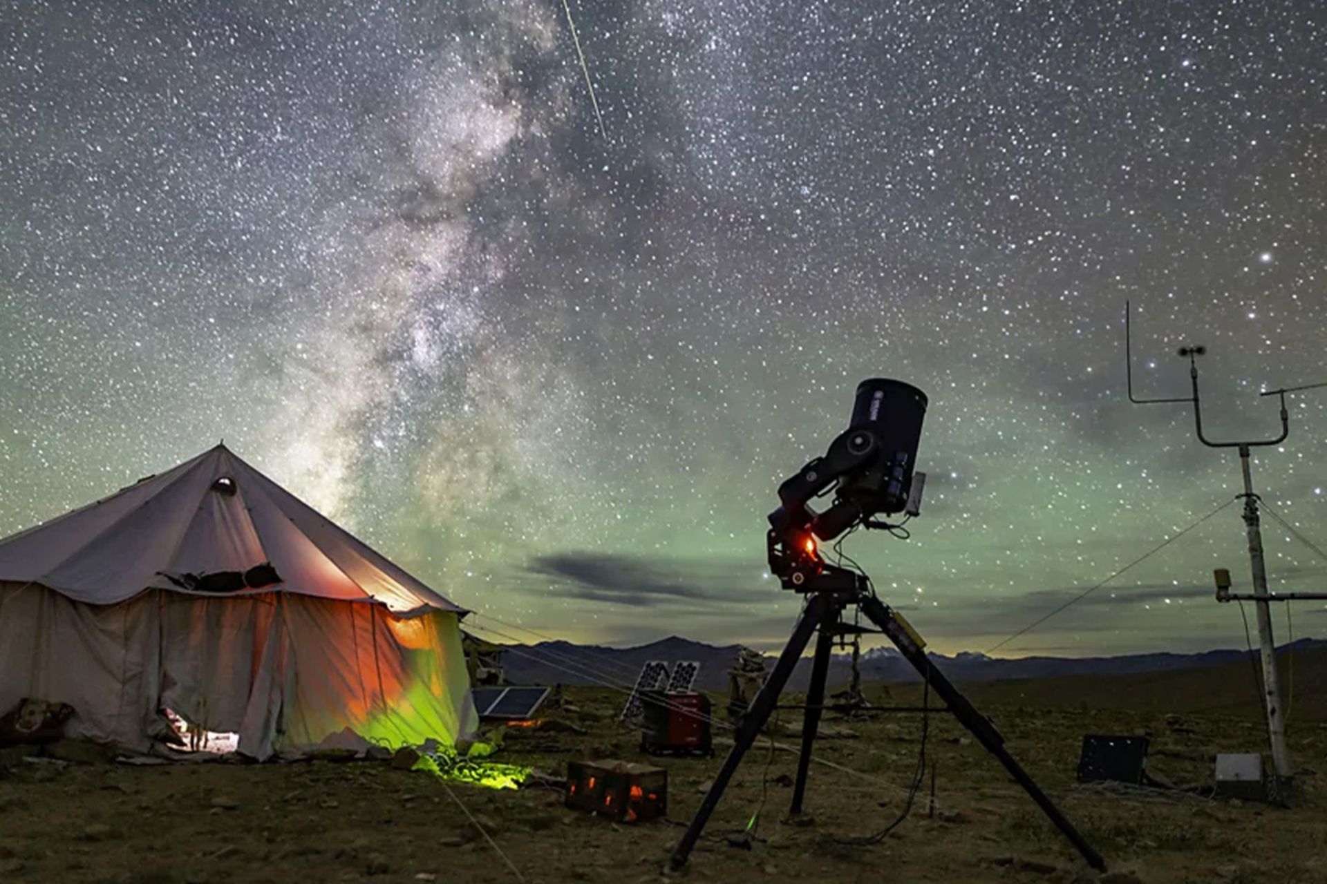 چادری روشن از داخل و یک تلسکوپ در فضای باز زیر آسمان پرستاره هانله