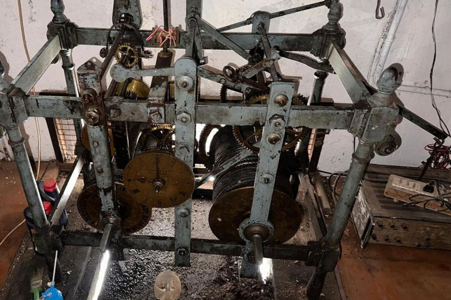 نمای کلی از مکانیزم داخلی و چرخ‌دنده‌های عظیم فلزی ساعت تاریخی در بالای برج کلیسا