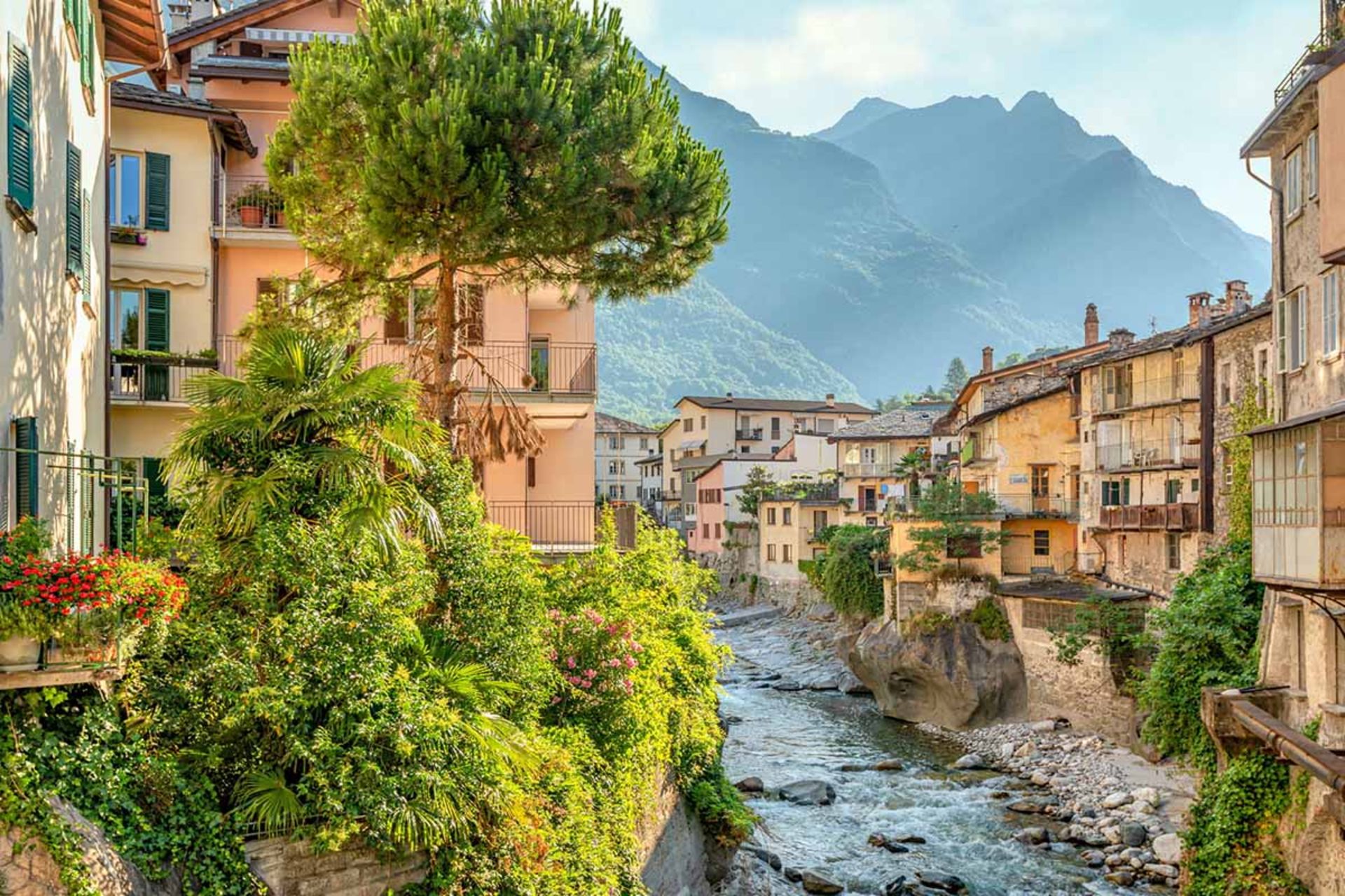 رودخانه زلال و خروشان در حال عبور از میان خانه‌های قدیمی با نماهایی به رنگ‌های گرم