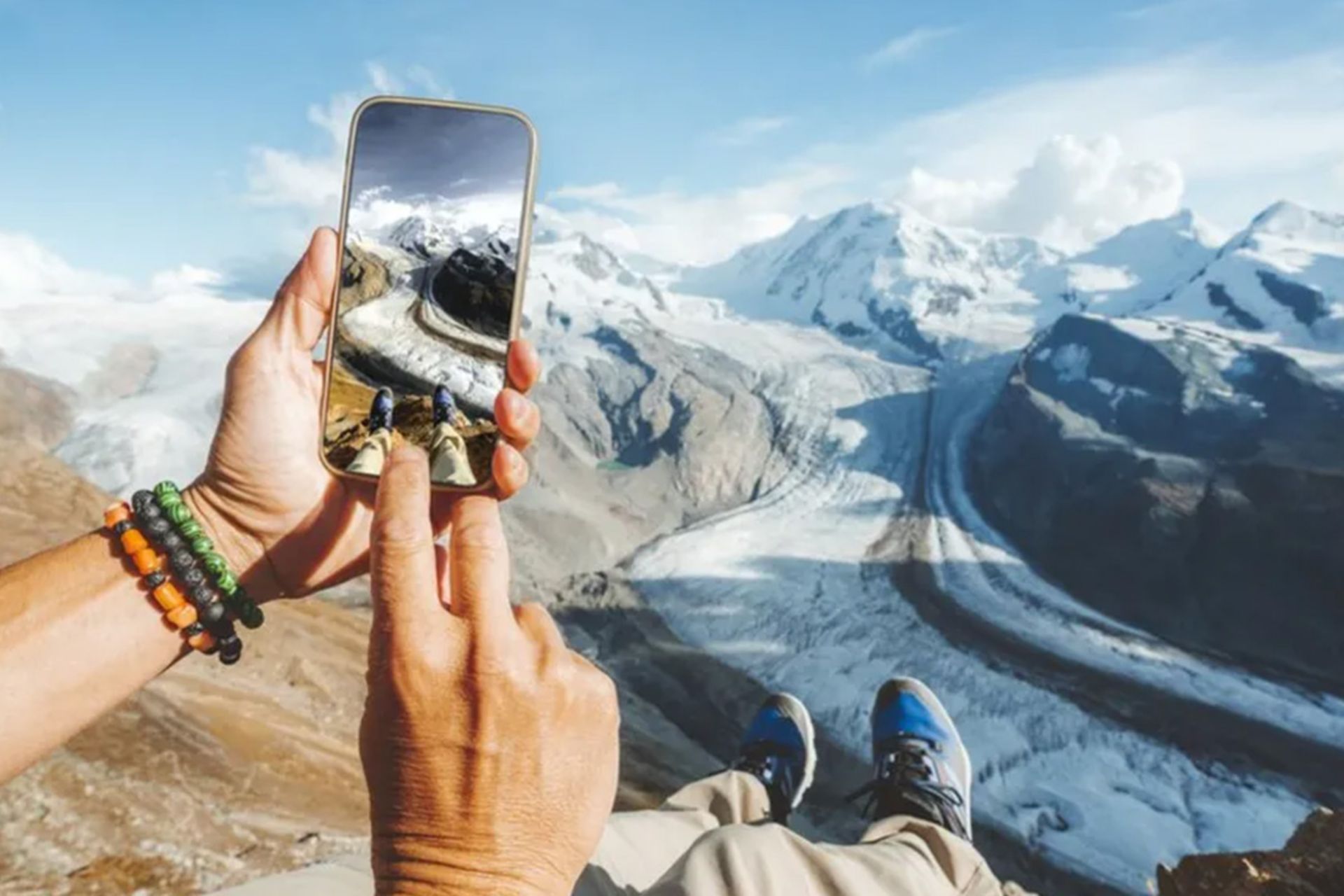 دستی که گوشی موبایل را به سمت کوه گرفته 