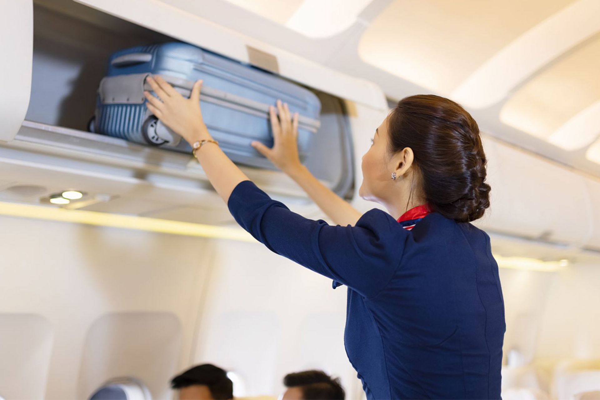 مهماندار هواپیما در حال قرار دادن چمدان در محفظه بار