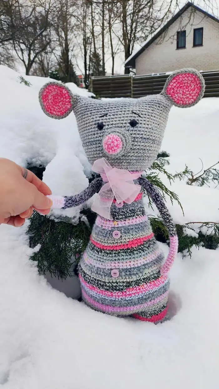 عروسک بافتنی موشی (Crochet Mouse) با بدن خاکستری و خطوط رنگی در میان برف