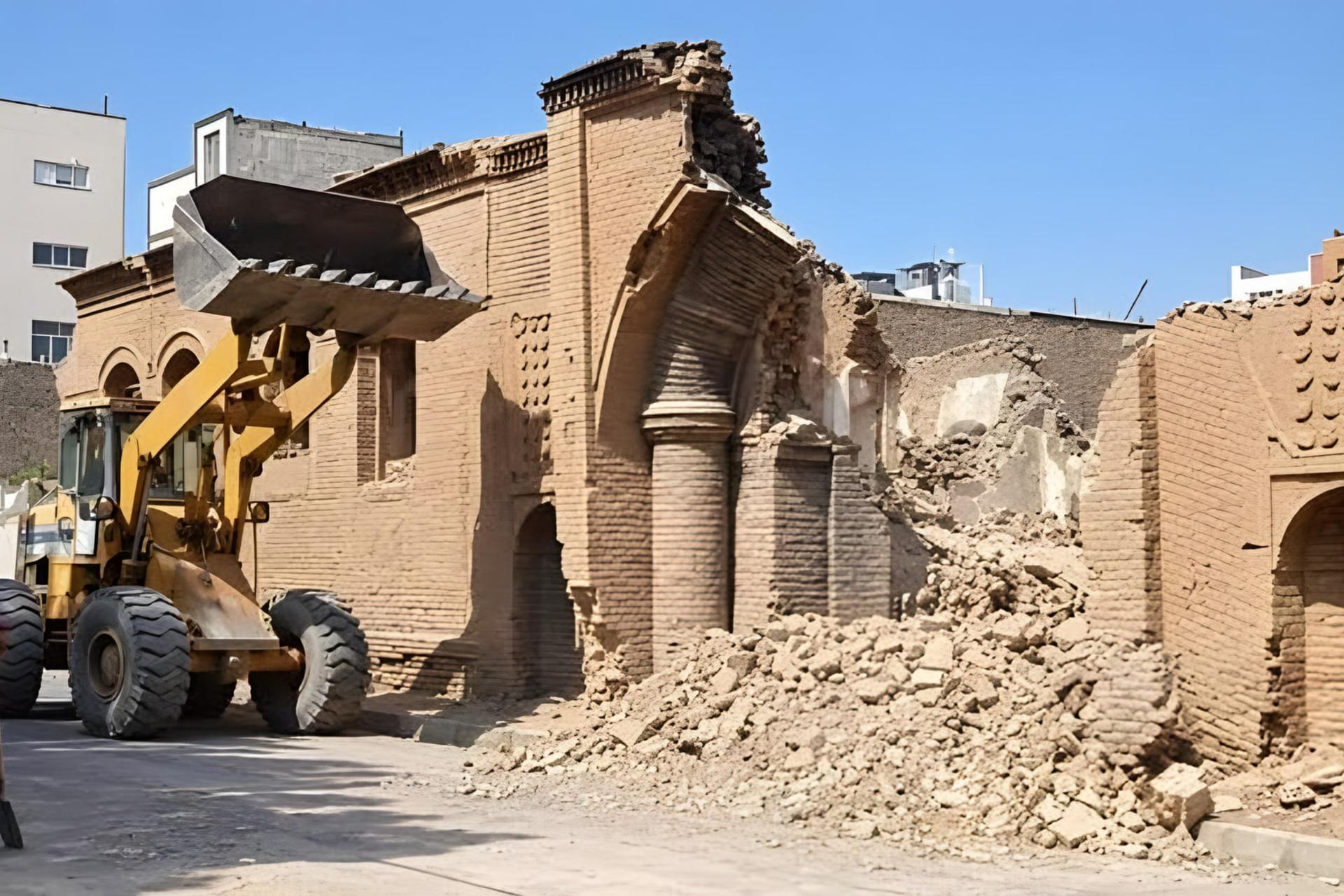 لودر در حال تخریب دیواره‌های آجری ورودی کاروانسرای سبزوار