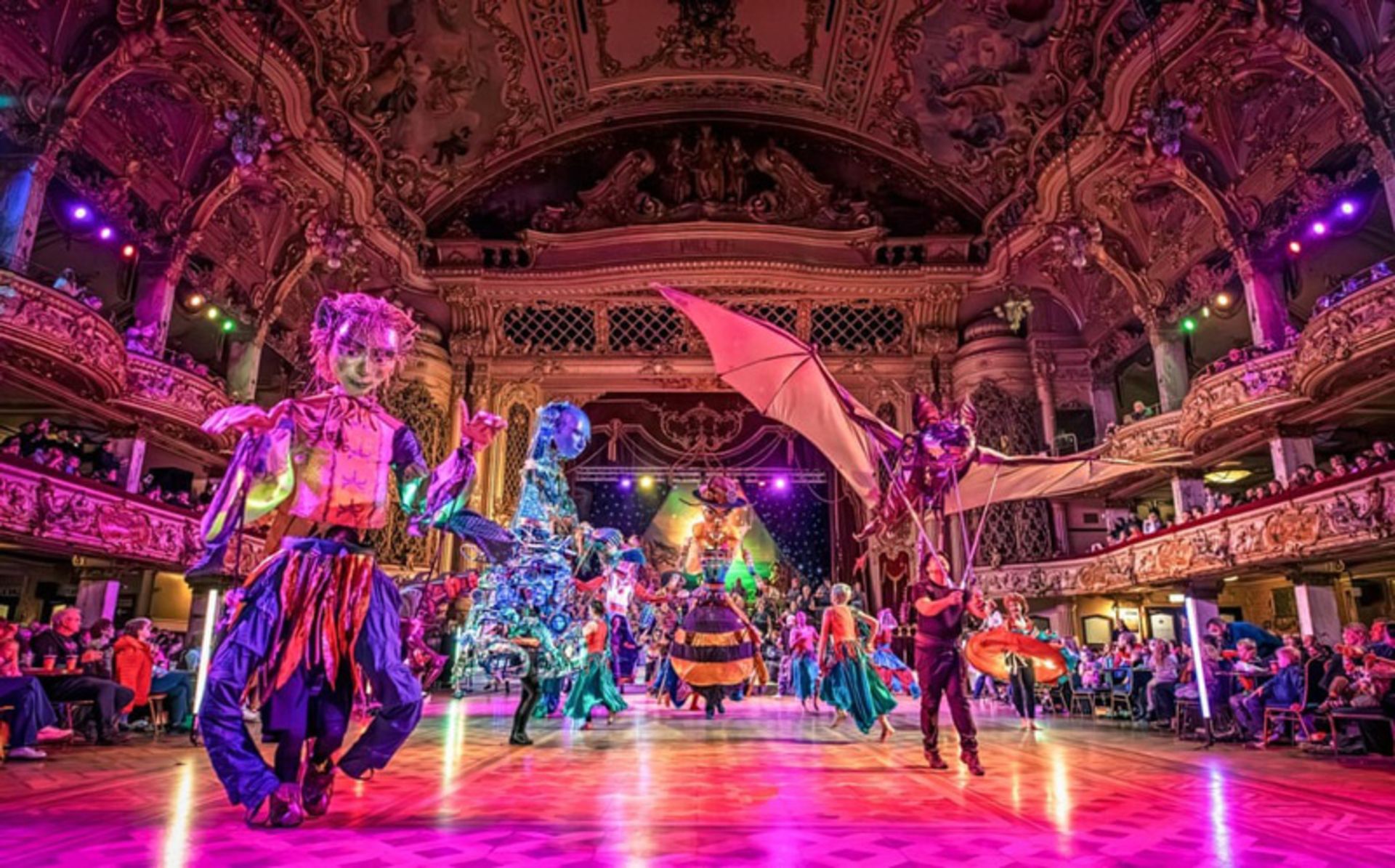 گروه رقص با لباس‌های محلی و رنگارنگ در یک سالن مجلل داخلی در بریتانیا