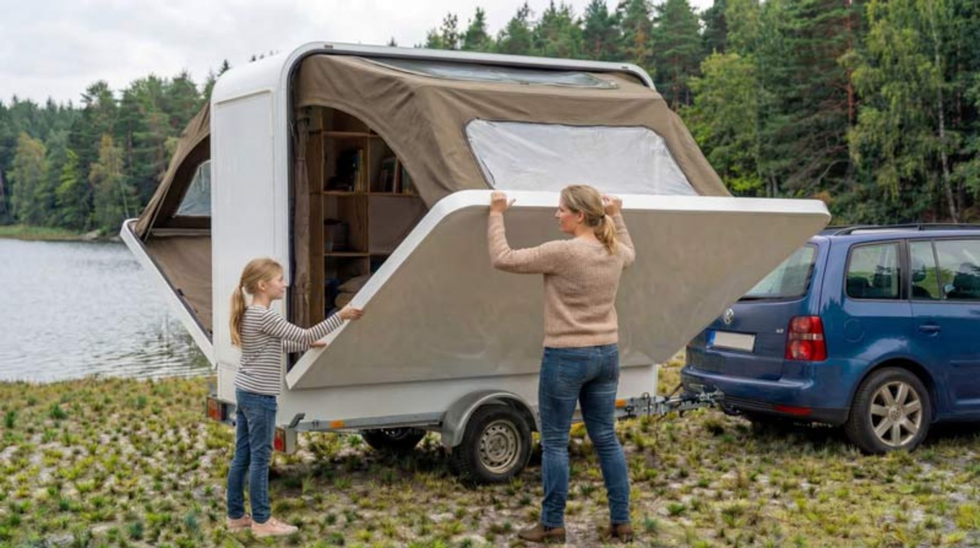 یک زن و دختر جوان در حال باز کردن دستی یکی از دیواره‌های جانبی سفید رنگ اتاقک