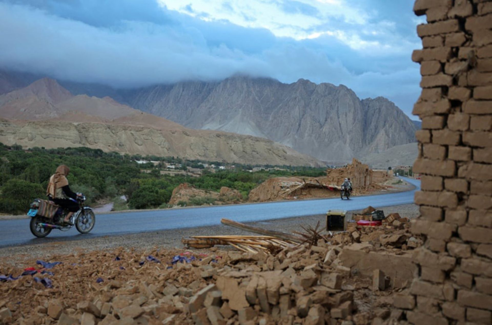 عبور مرد موتورسوار از کنار ساختمان‌های آسیب‌دیده در ولایت سمنگان افغانستان پس از زمین‌لرزه