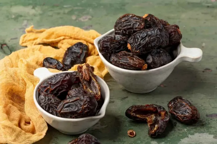 خرماهای خشک و رسیده در دو ظرف سفید کوچک روی میز