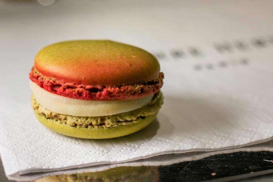 ماکارون (Macaron) رنگی با لایه‌های کرم و فیلینگ میوه‌ای روی دستمال کاغذی