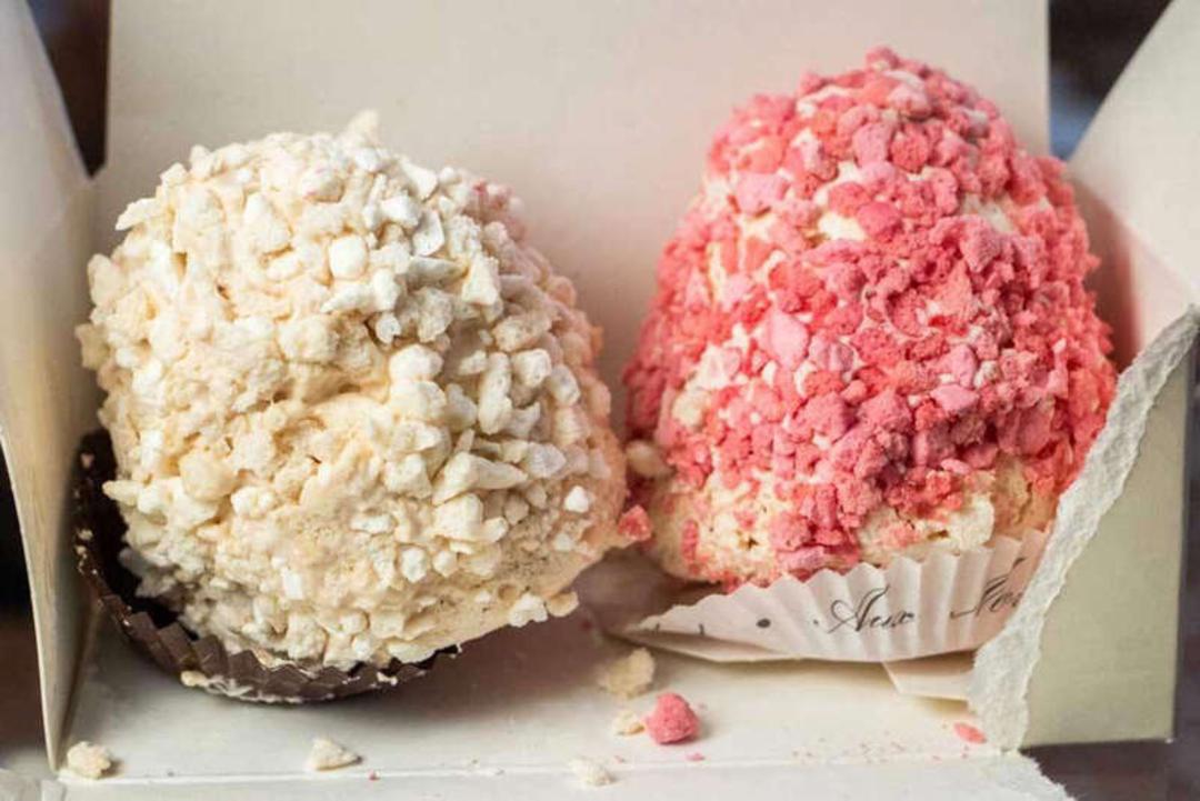 شیرینی‌های دیسپرز (Creampuff) با پوشش تکه‌های ترد سفید و صورتی در جعبه
