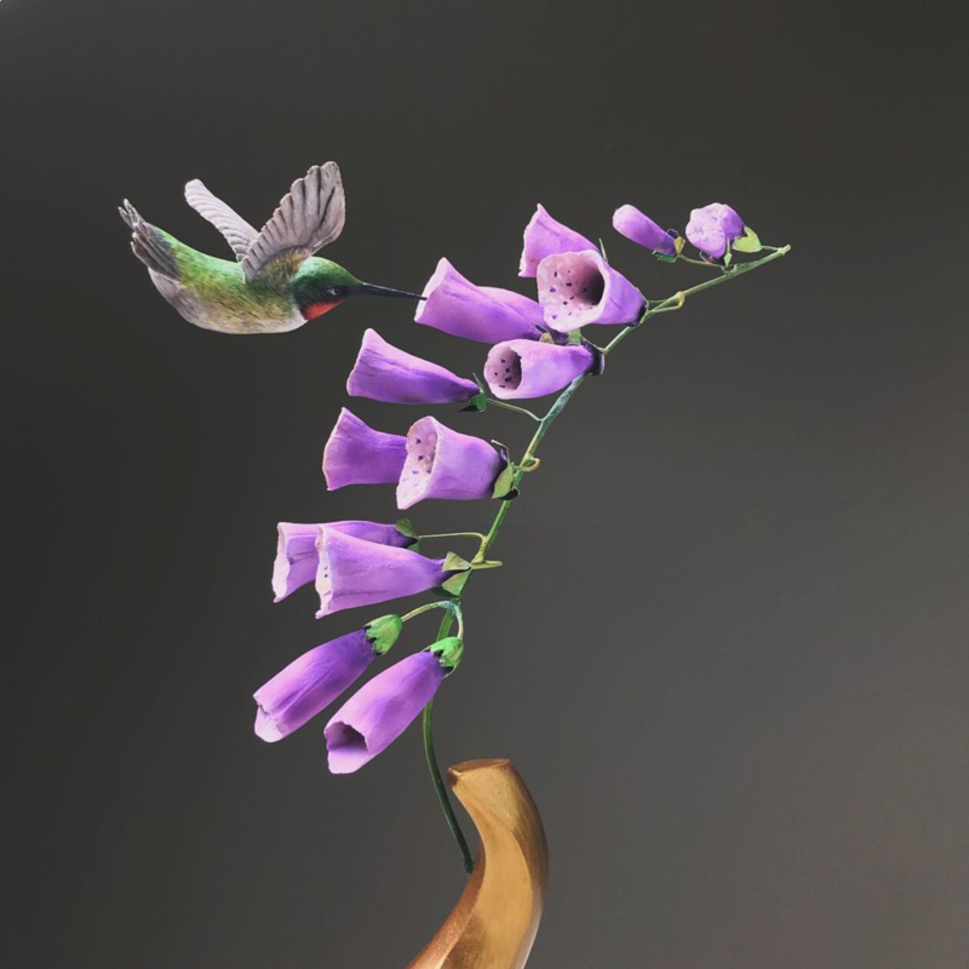 مجسمه چوبی مرغ مگس‌ خوار کنار گل