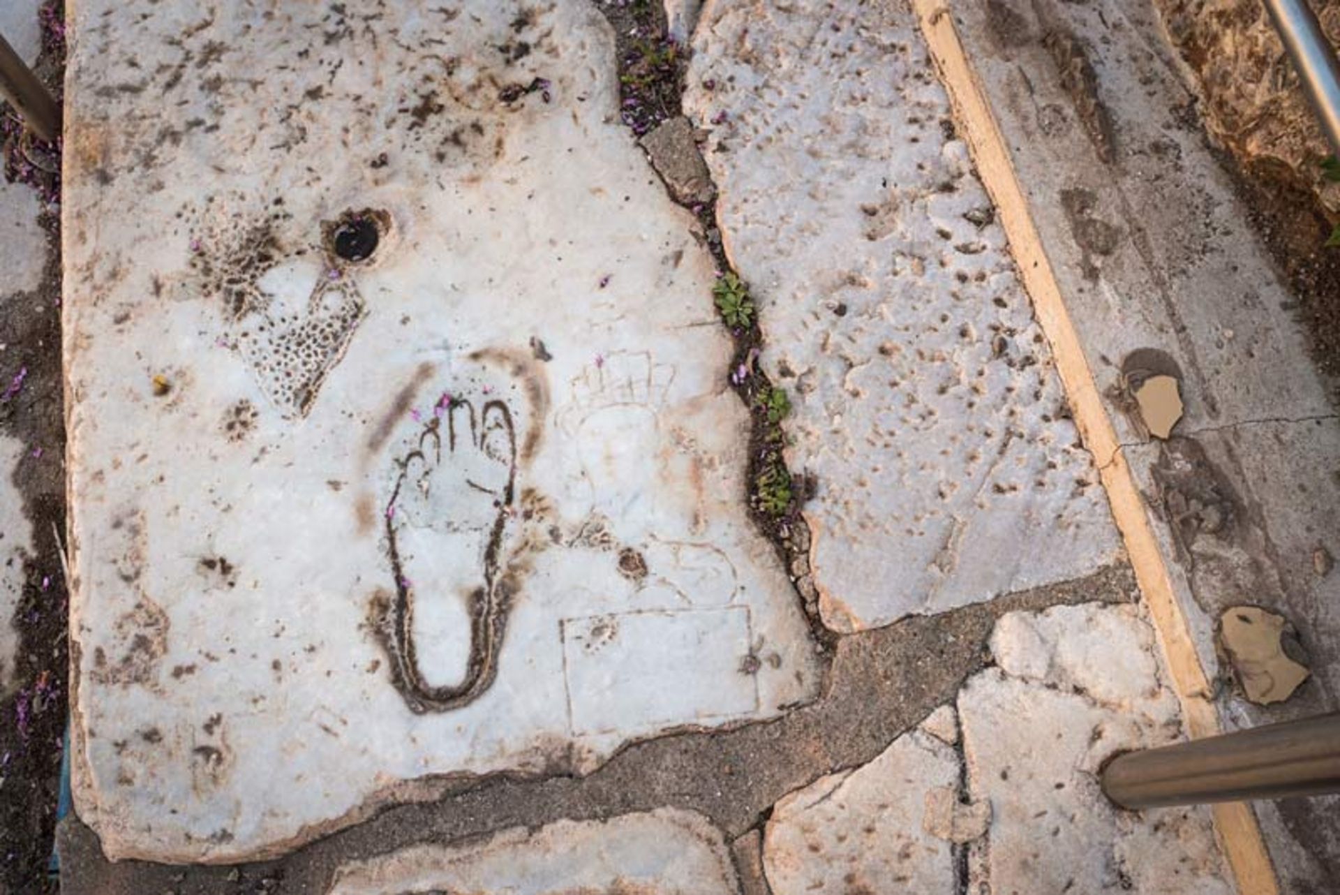 حکاکی باستانی ردپا و چهره زن بر سنگ‌فرش مرمرین خیابان‌های افسوس