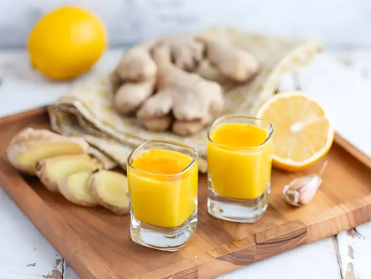 شات زنجبیل (Ginger) و لیمو در لیوان‌های کوچک روی تخته چوبی