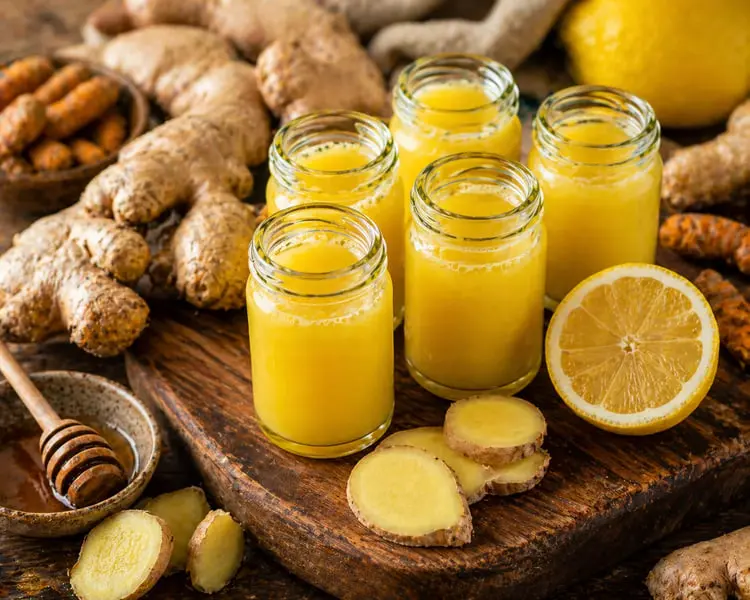 شات زنجبیل (Ginger) و لیمو در لیوان‌های کوچک شیشه‌ای روی تخته چوبی