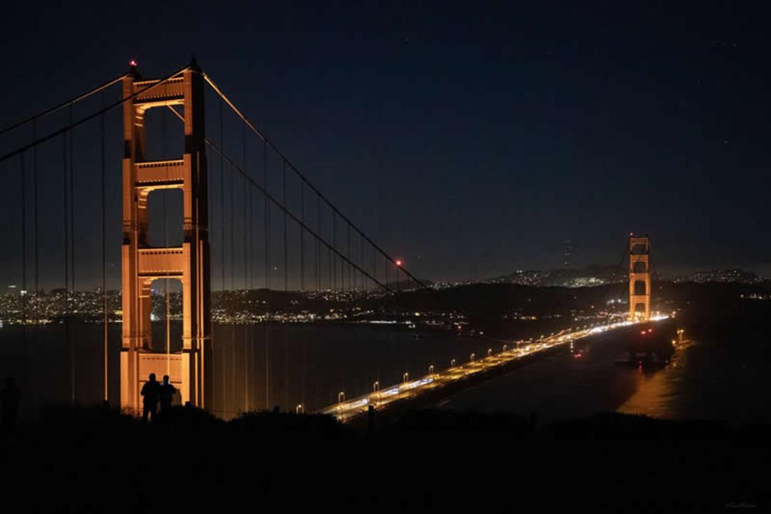 پل گلدن گیت (Golden Gate Bridge) در شب با نورپردازی گرم و درخشان