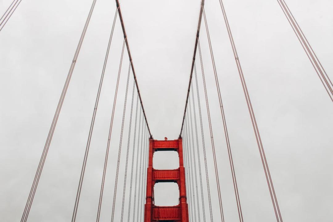سازه و کابل‌های قرمز رنگ پل گلدن گیت (Golden Gate Bridge) در آسمان ابری
