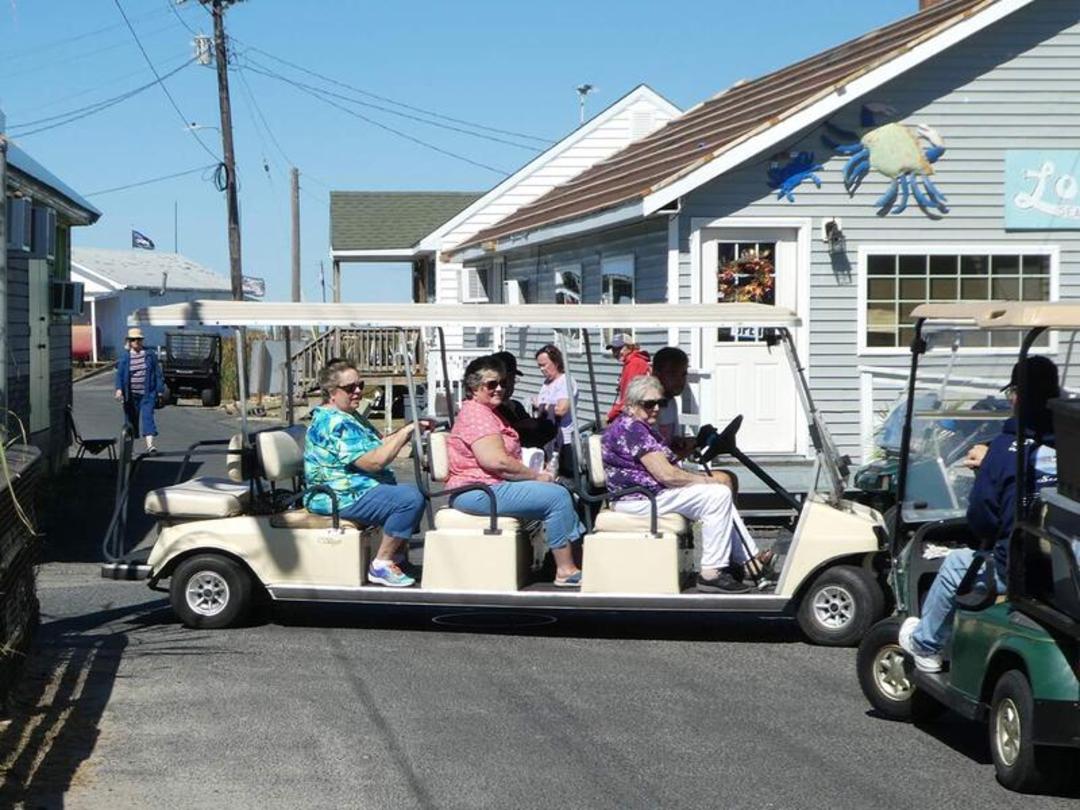 گولف کارت (Golf Cart) حامل مسافران در یک خیابان ساحلی