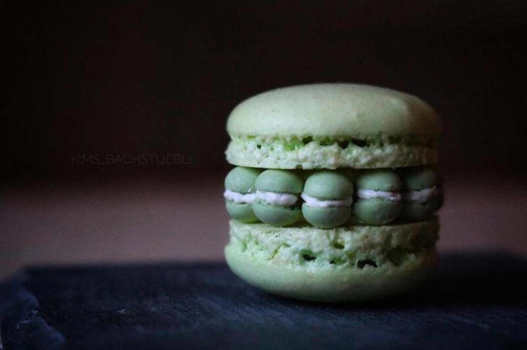 ماکارون (Macaron) سبز رنگ با لایه‌های کرم و توپ‌های کوچک پسته